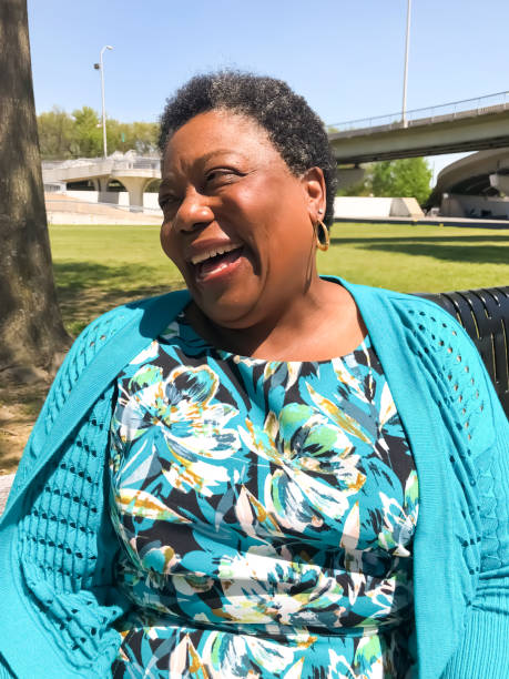 Woman laughing in park An African American woman enjoys a warm spring day in the park. michael dean shelton stock pictures, royalty-free photos & images
