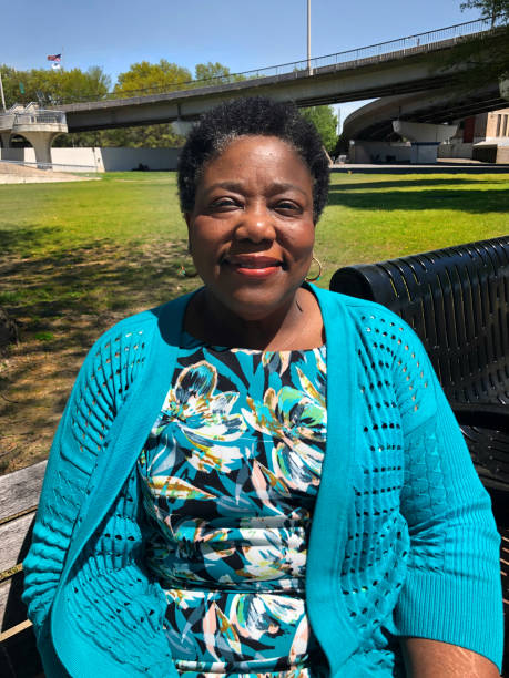 Portrait of a Smiling Woman Sitting Outdoors An African American woman enjoys a warm spring day in the park. profile view photos stock pictures, royalty-free photos & images