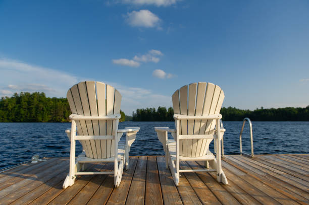istock Two white Adirondack chairs on a wooden dock 1257088781