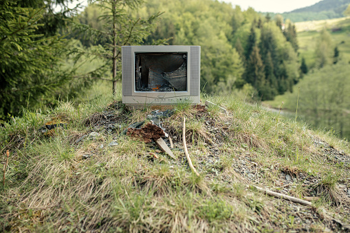 Old broken crt television dumped in nature in forest on mountain.