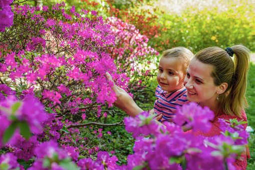 Beautiful, young woman  and her daughter among flowers