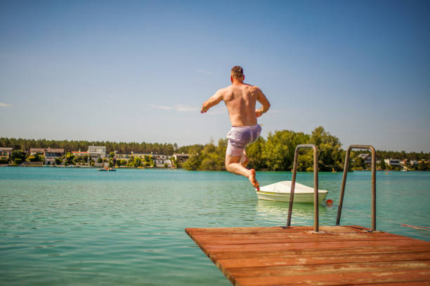 istock Young man jumping off of a dock into Lake 1257092780