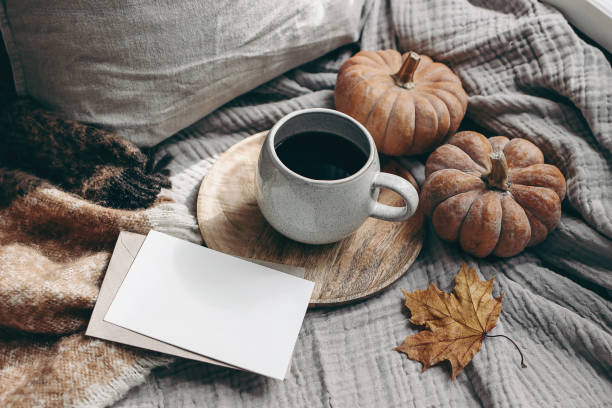 istock Fall feminine styled composition. Autumn breakfast still life. Blank greeting card mock-up scene with cup of coffee, wool blanket, maple leaf and pumpkins. Cotton table cloth background. Thanksgiving 1257093890