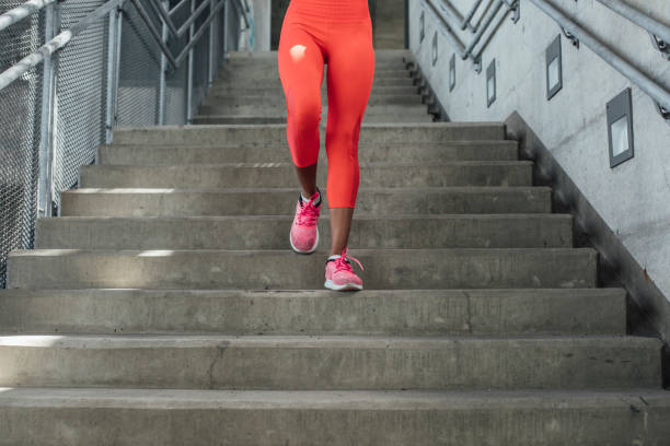 Legs of unrecognisable sportswoman in tights running downstairs.