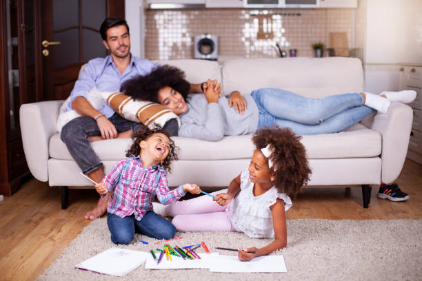 istock Kids playing on floor, parents relaxing on sofa at home 1257095373