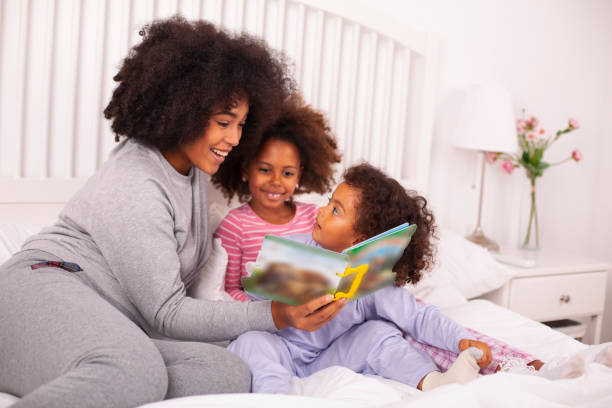 istock Mother with daughters reading books in bed 1257095391
