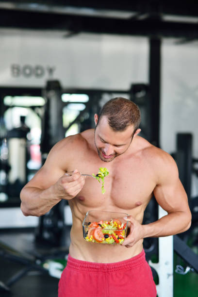 istock Powerful athletic man with great physique eating a healthy salad. 1257095404