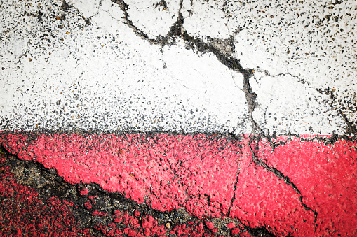 A white and a red line of asphalt, road with red and white painted line on the edge. horizontal background concept, with cracked painted asphalt street, space for text