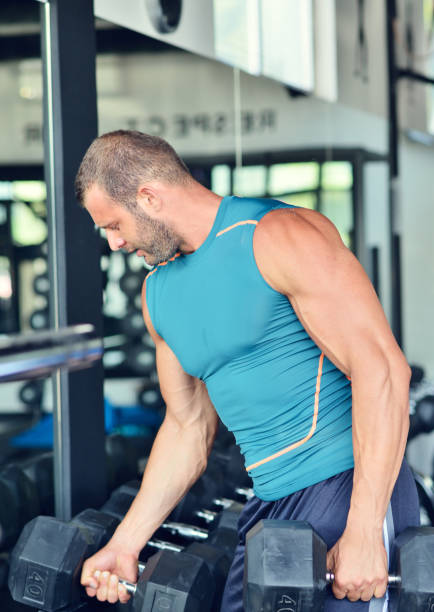 istock Man at the gym. Man makes exercises with barbell 1257100141