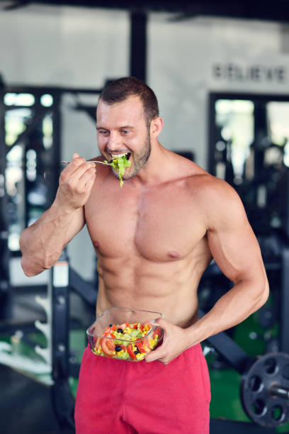 istock Powerful athletic man with great physique eating a healthy salad. 1257101262