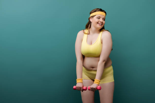 istock Plus size sportswoman training with dumbbells and smiling on green 1257101522