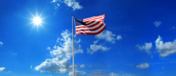 istock American flag at flagpole over sunny blue sky and shinning sun 1257103201