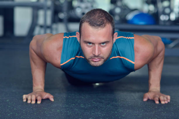 istock Man at the gym. Man makes exercises with barbell 1257103202