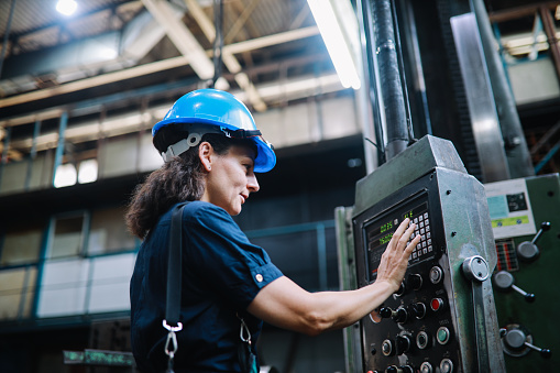 Image of a woman working as a technical manual operator in the STEM sector. She is working in a heavy industry production facility.