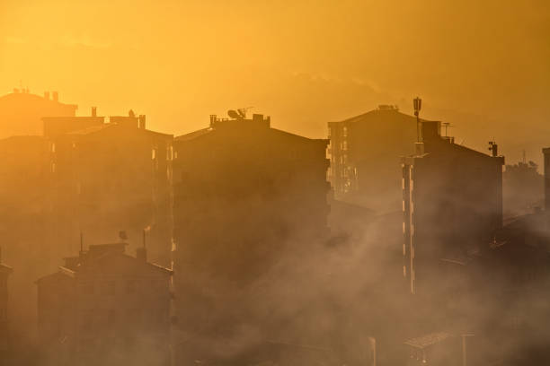 environmental air pollution concept of smog and cityscape early morning silhouetted buildings in smoke, winter time air pollution photos stock pictures, royalty-free photos & images