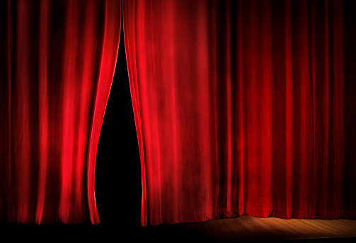 close up red stage curtain opening over black background