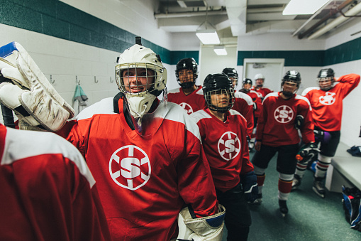 A women's hockey team dressed up in their recreation league uniforms is ready to hit the ice pre game. They are posing in the female locker room before their game. Image taken in Utah, USA.