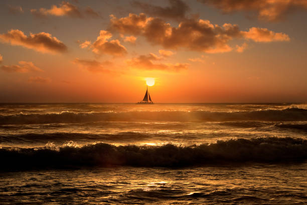 barca a vela sagomato che galleggia su paesaggi marini color arancione sul cielo al tramonto - horizon over water horizontal surface level viewpoint foto e immagini stock