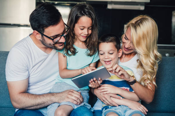 Young family and modern technologies. Portrait of a happy family with two children using digital tablet in the living room. family dependency mother family with two children stock pictures, royalty-free photos & images