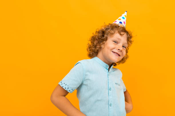 istock Smiling red-haired curly boy with a celebratory cap isolated yellow background 1257108371
