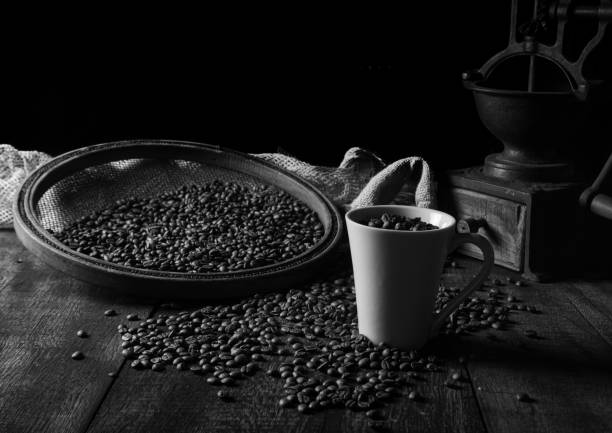 Roasted coffee on rustic wood, cup, grinder and more with black background, selective focus