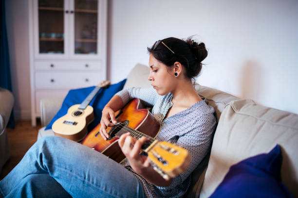 istock Young female sitting playing  guitar online guitar lessons 1257108942