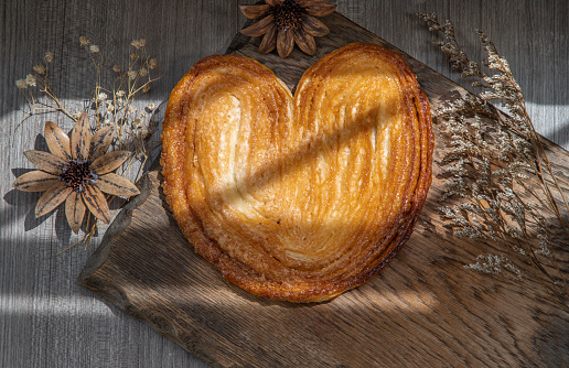 Butter Palmier bread, French pastry in palm leaf or a butterfly shape sometime look like pig's ear or elephant ear on rustic wooden board. Selective focus.