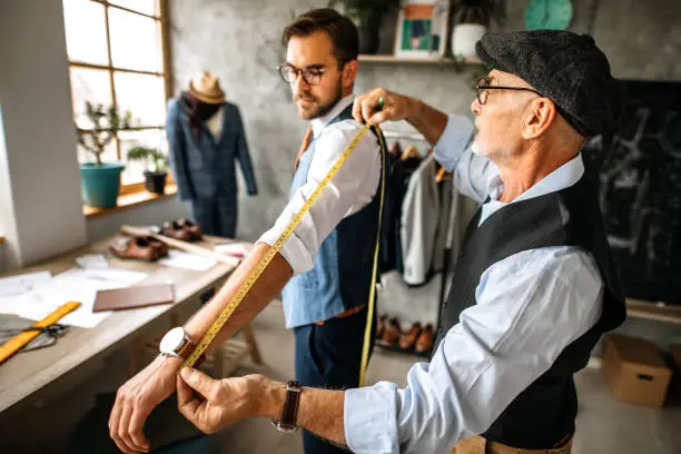 Senior Fashion Designers Taking Measurements of His Customer in Clothing Design Studio.