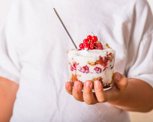 Layered trifle dessert with sponge cake, whipped cream and raspberries in child hands Layered trifle dessert with sponge cake, whipped cream and raspberries in child hands yogurt fruit biscotti berry fruit stock pictures, royalty-free photos & images