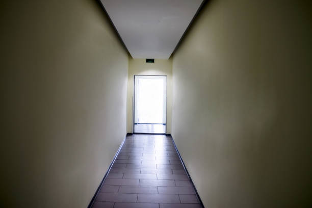 A long corridor with an open door. A bright light shines from the open door.