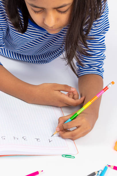 istock Cute left-handed girl is writing with a pencil in her notebook. 1257114381