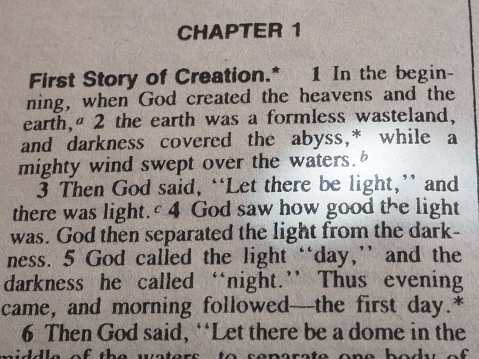 First part of Bible in Genesis where God creates light. Image shows few lines of text with the word light highlighted with a white ray of light.