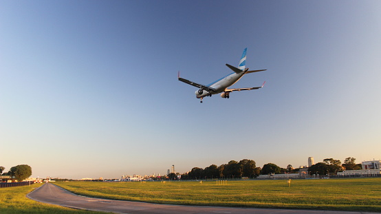 Buenos Aires, Argentina: airplane landing at the runway of the Aeroparque Jorge Newbery International Airport, with some trees on the background and large areas of grass