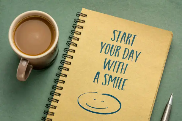 start your day with a smile inspirational note - handwriting in a sketchbook with a cup of coffee, lifestyle, business and positivity concept