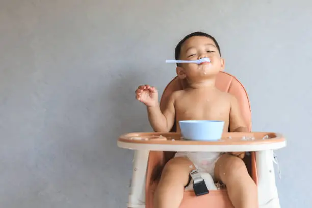 Photo of Asian baby boy eating food by himself
