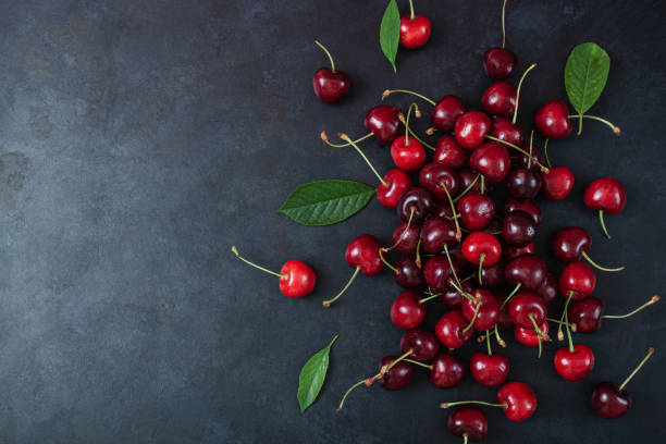 Cherry with leaf on plate and water dropsand on grey stone table