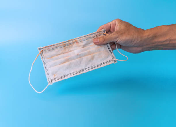 istock Man hand holding used face mask on blue background 1257124930
