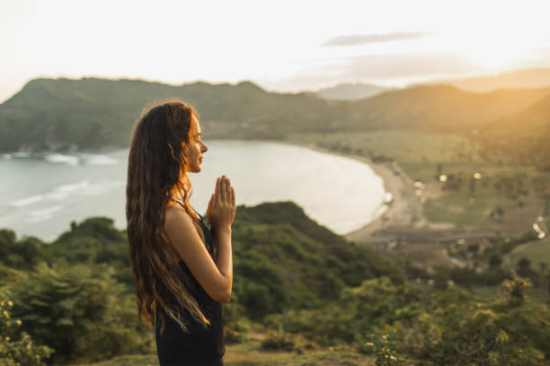 kobieta modląc się samotnie o wschodzie słońca. tło przyrody. koncepcja duchowa i emocjonalna. wrażliwość na naturę - spirituality yoga zen like meditating zdjęcia i obrazy z banku zdjęć