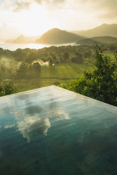 istock Infinity pool with amazing mountain and ocean view at sunset. Sun rays and mist. Cloud reflection in water. Luxury hotel viewpoint. 1257130596