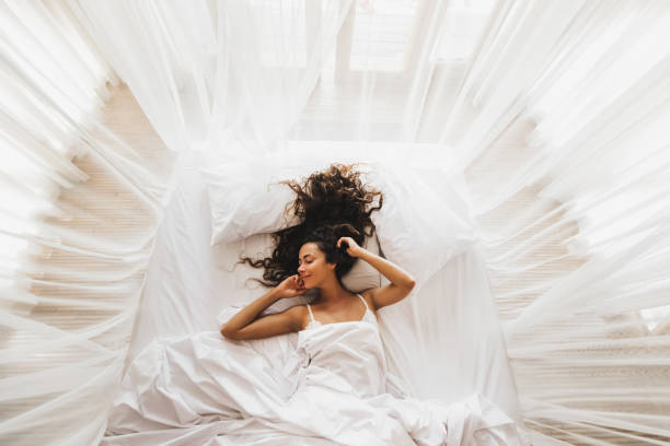 Beautiful smiling girl awakening in white bed. Happy wake up and start new day. Leisure and rest. View from above. Wellbeing concept. Beautiful smiling girl awakening in white bed. Happy wake up and start new day. Leisure and rest. View from above. Wellbeing concept. sensuality stock pictures, royalty-free photos & images