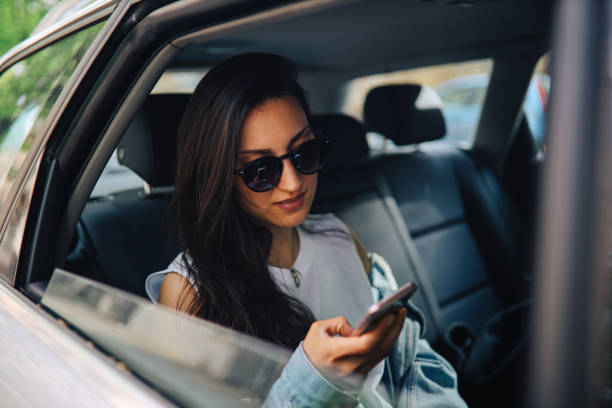 istock Young woman using smartphone in a cab or car share 1257131420