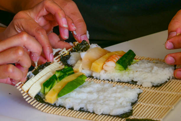 istock Rolling home made sushi rolls at home in the kitchen 1257135741