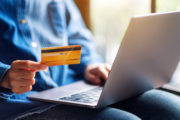 istock a woman holding credit cards while using laptop computer 1257137110