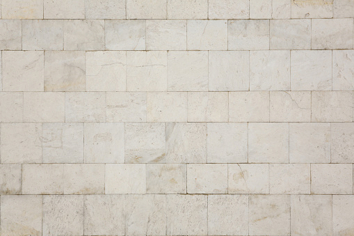 Natural texture and background. The wall of the house is covered with white marble tiles.