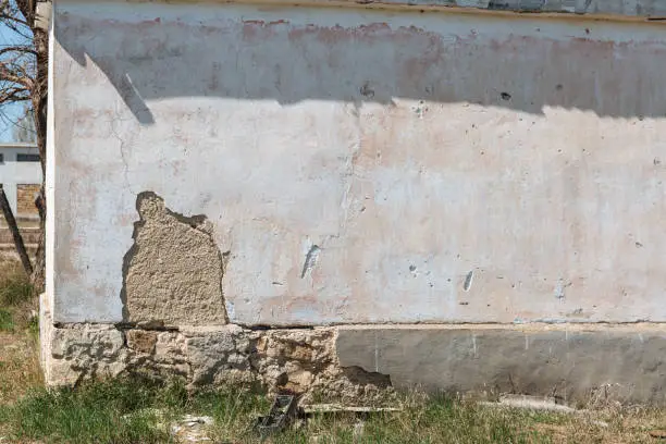 Plaster peeling off brick wall. The foundation of a residential building is gradually collapsing.