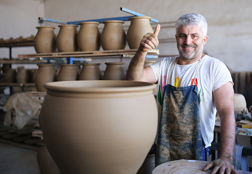 Unrecognizable person making pottery vessel on wheel.
