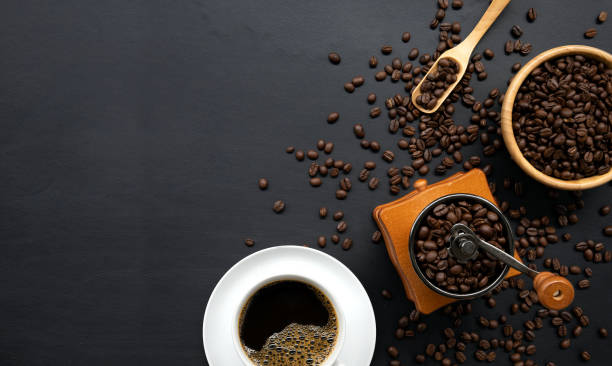 istock hot coffee, bean and hand grinder on black table background. space for text. top view 1257150141