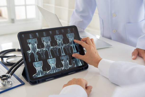 cervical vertebrae spine x-ray image Doctor check up cervical vertebrae spine x-ray image on digital tablet screen with medical team for consult. cervical vertebrae photos stock pictures, royalty-free photos & images