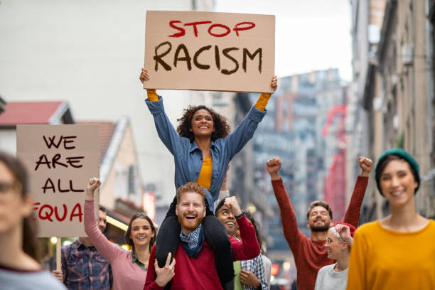 multitud de personas marchan contra el racismo en la calle - antirracismo fotografías e imágenes de stock