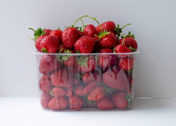 Fresh strawberries in plastic container isolated on white background in horizontal format Fresh, ripe strawberries in clear plastic container isolated on white background in horizontal format. punnet strawberries stock pictures, royalty-free photos & images